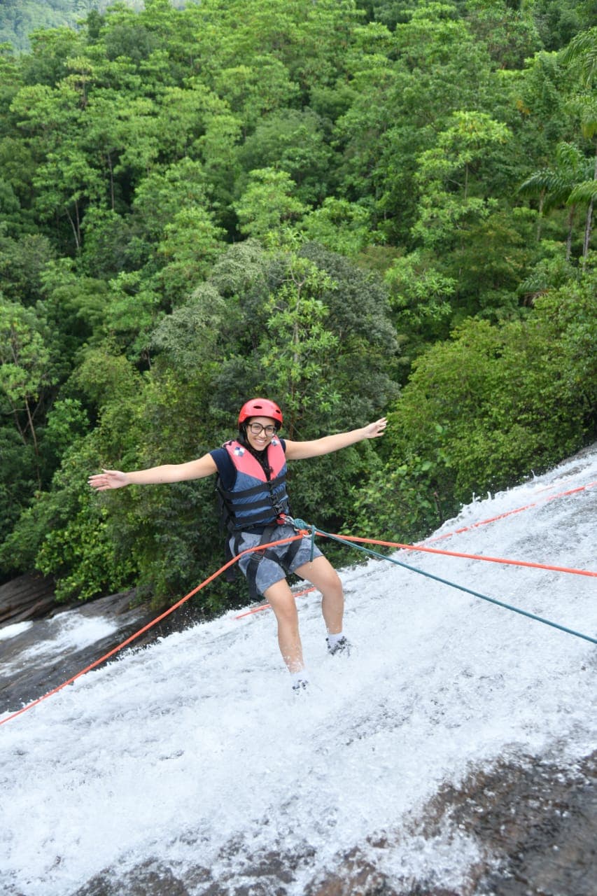 Cliff jump from high rock ledge into deep jungle pool