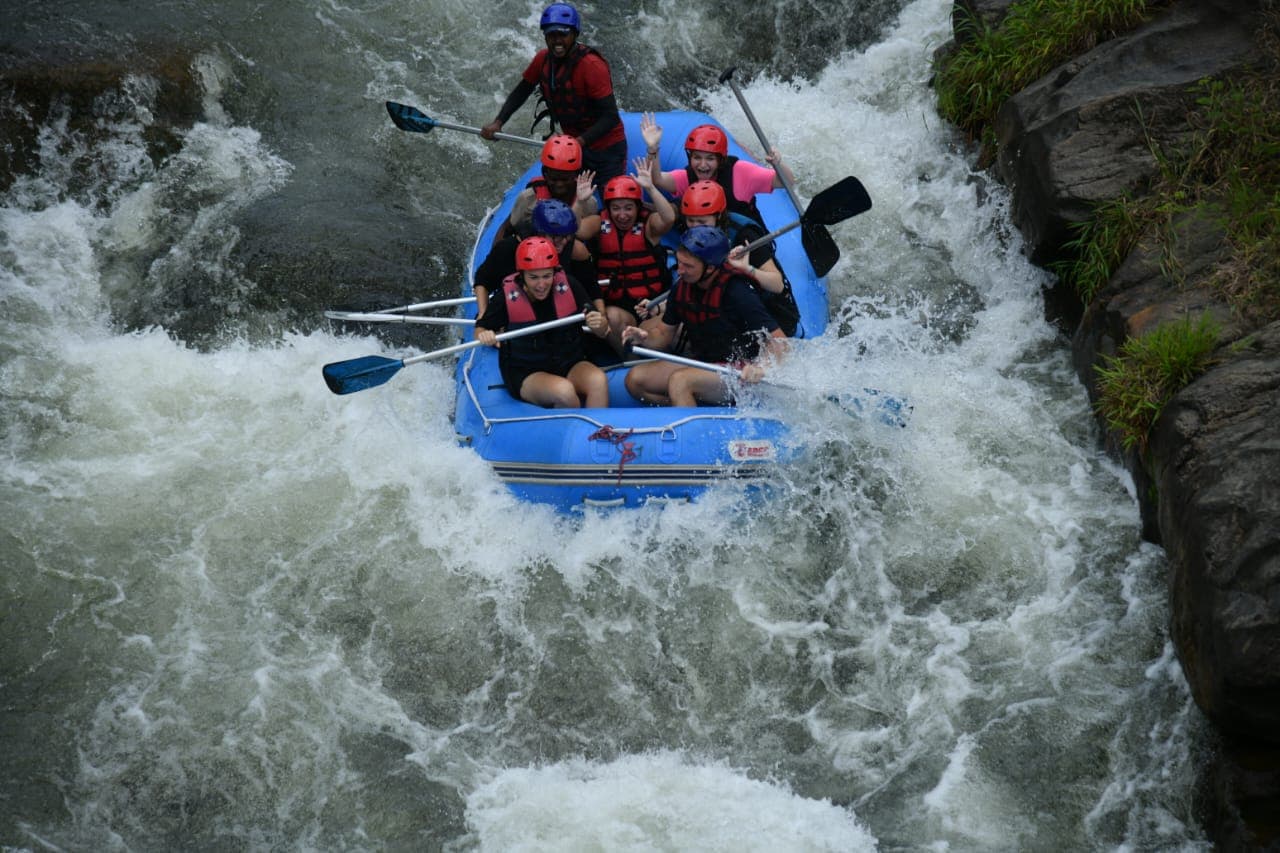 White water rafting team paddling through river white foam