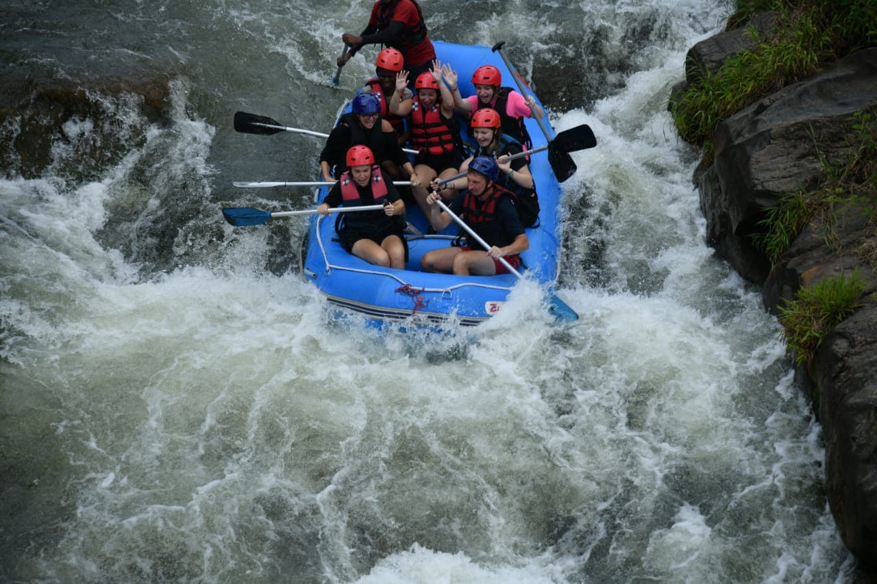 Rafting team powering through river waves and spray