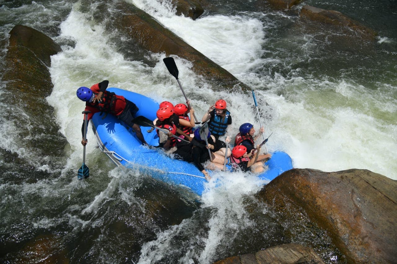 Rafters maneuvering near river boulders with safety gear